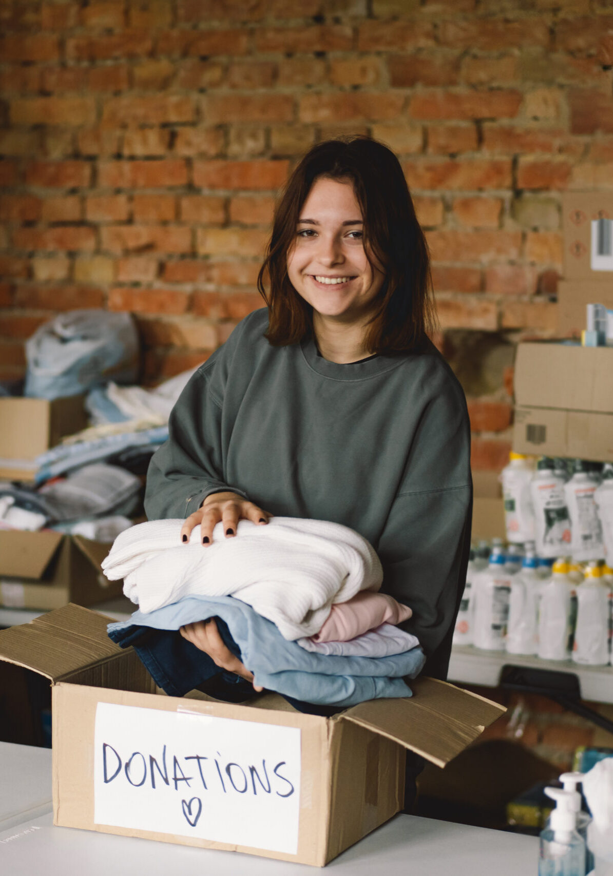 Volunteer teengirl preparing donation boxes for people. Donation clothing for refugees, support of war victims. Humanitarian aid concept.Helping people