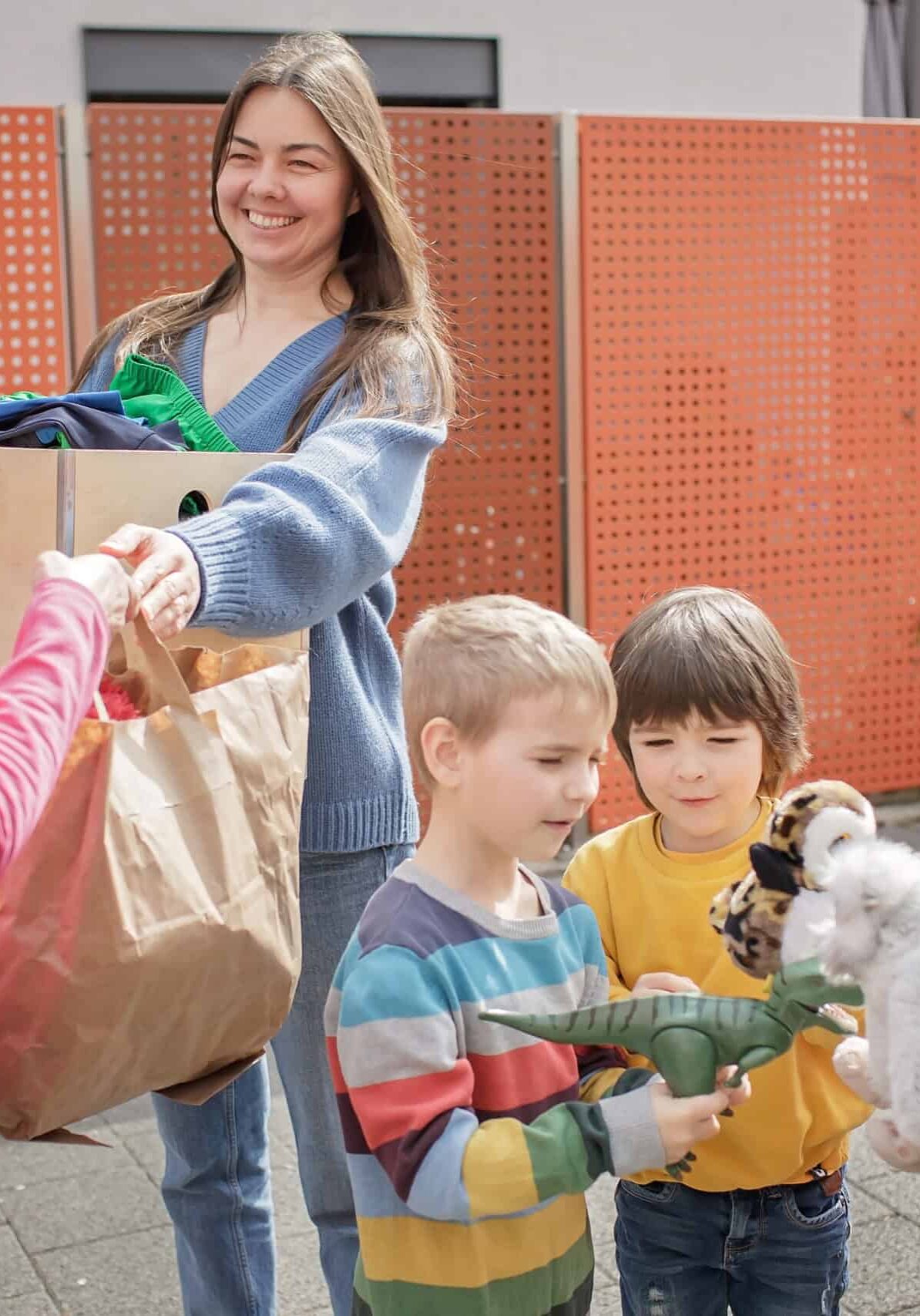 A senior woman gives Ukrainian family of refugee clothes and toys to support them because they had to flee Russian attack. Humanitarian aid and helping hand from world for Ukraine during the war
