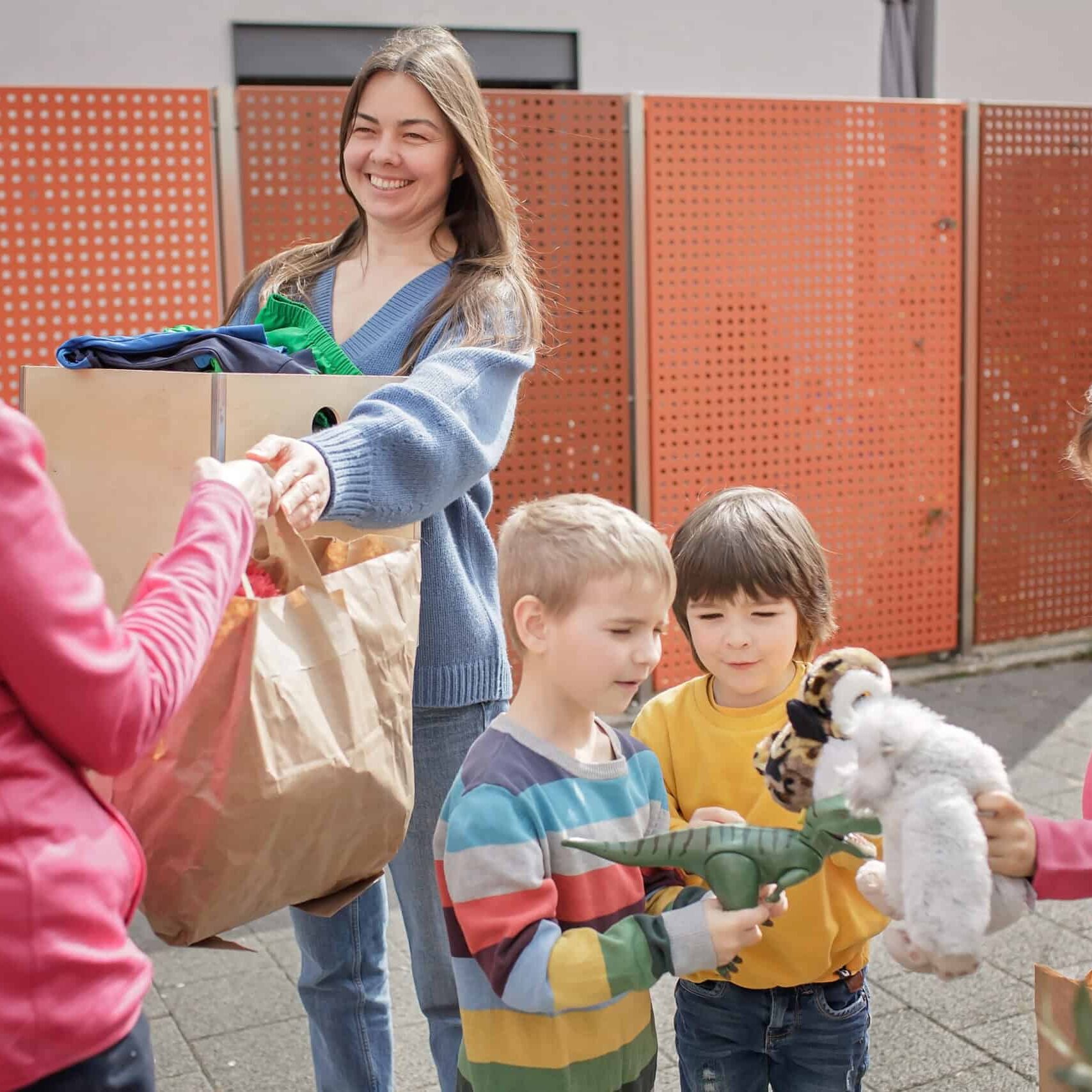 A senior woman gives Ukrainian family of refugee clothes and toys to support them because they had to flee Russian attack. Humanitarian aid and helping hand from world for Ukraine during the war